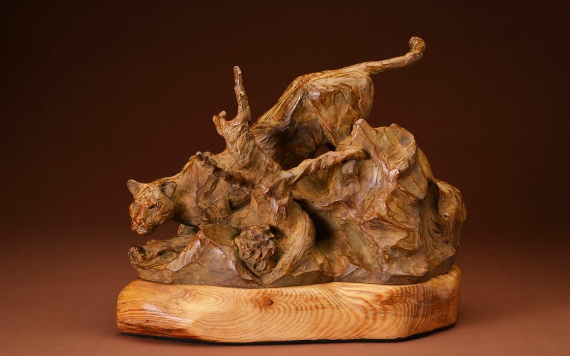 A bronze mountain lion sculpture by Scott Mortensen, shown mid-stride.